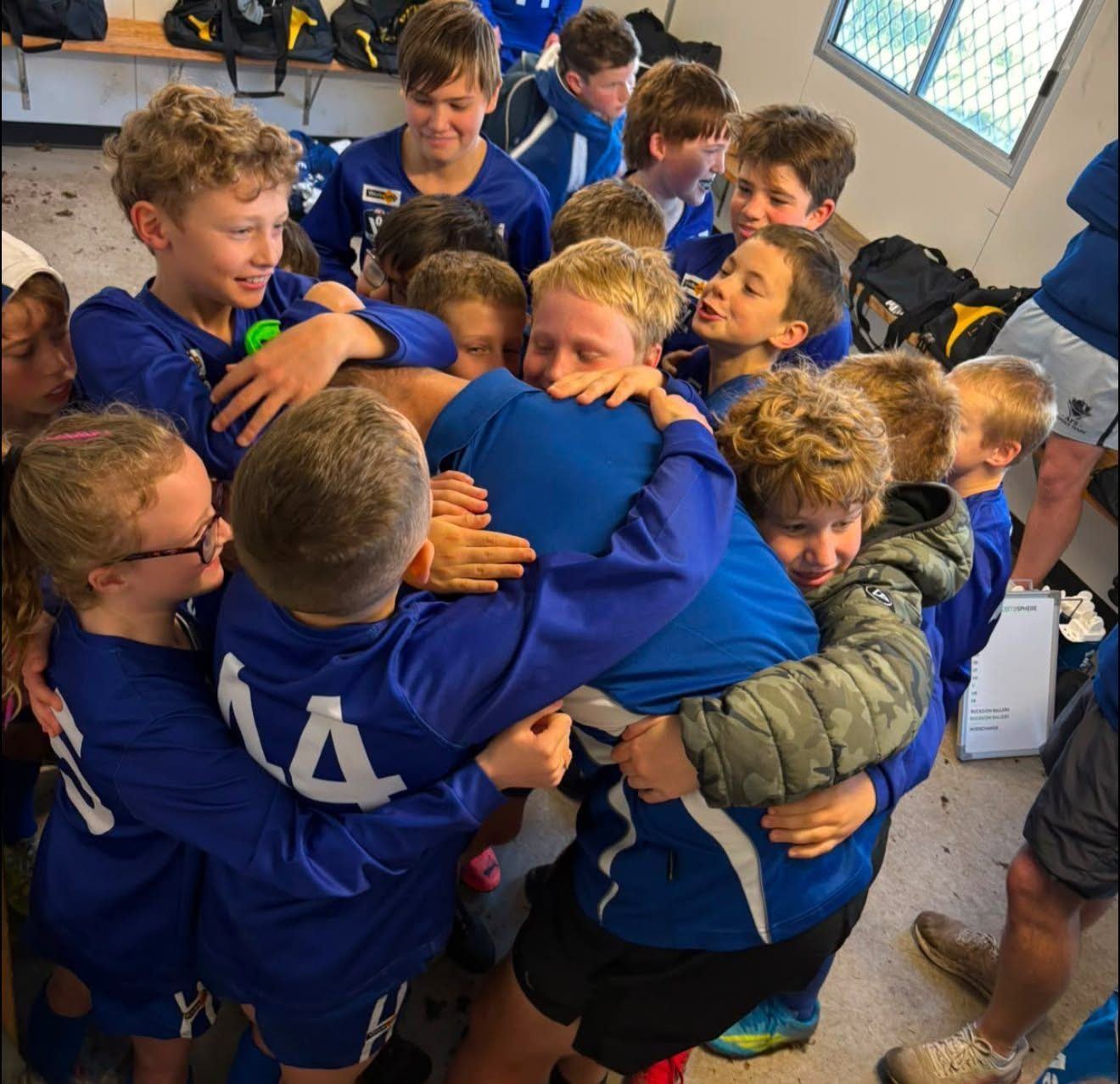 Hastings junior players wrapped in a big team hug in the rooms after a game.